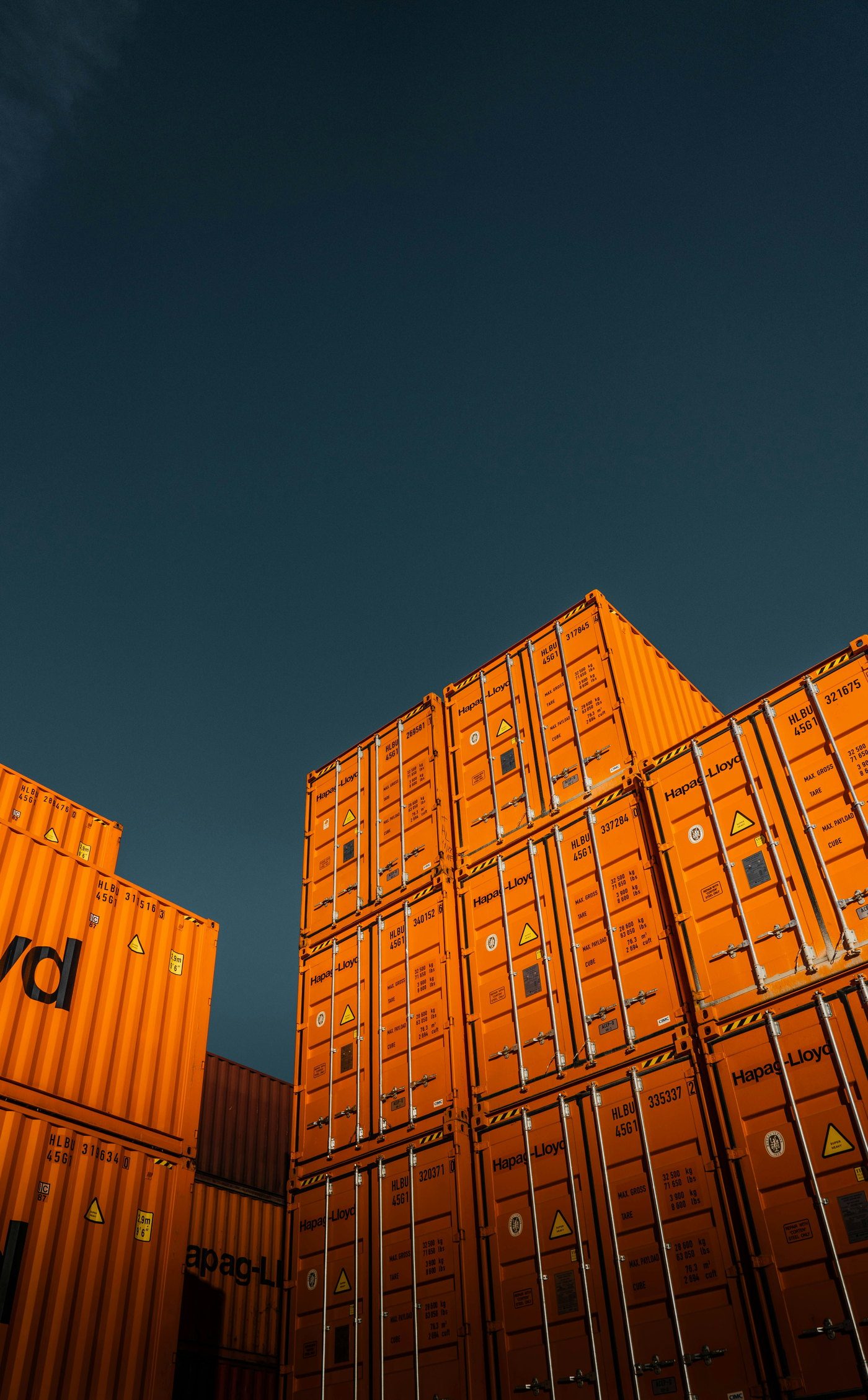 Stacked shipping containers in a port yard at dusk